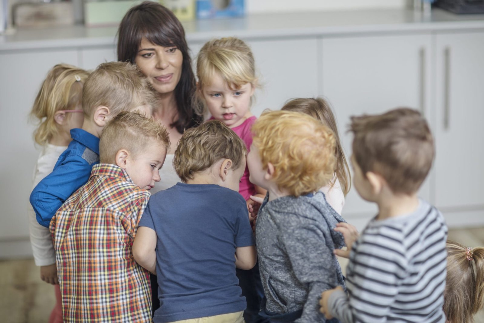 Teacher in classroom, surrounded by young children